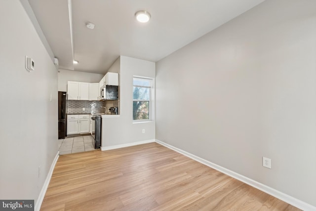 kitchen featuring appliances with stainless steel finishes, light hardwood / wood-style floors, white cabinetry, and tasteful backsplash