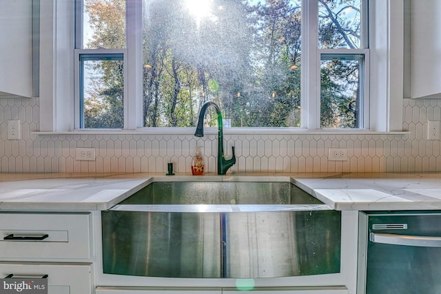 room details featuring tasteful backsplash, light stone counters, and white cabinets