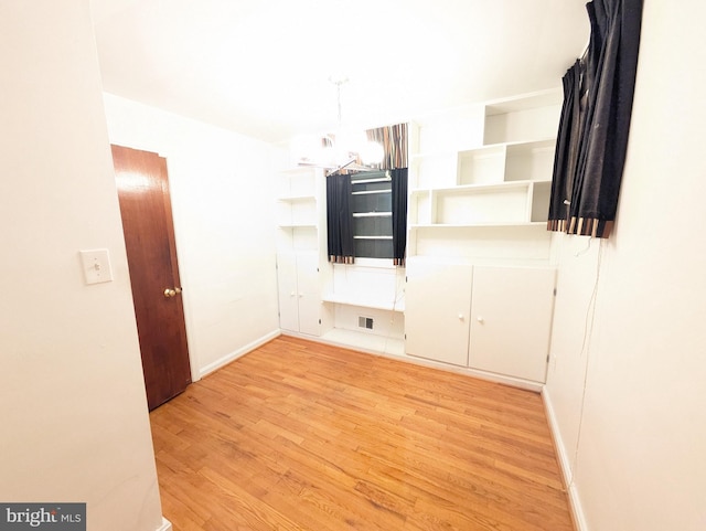 unfurnished room featuring a notable chandelier and light hardwood / wood-style flooring