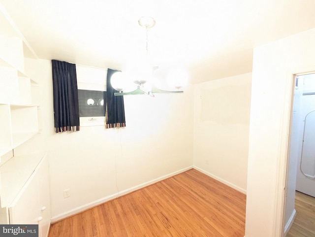 spare room with hardwood / wood-style floors and a chandelier