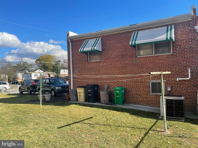 view of side of home with central AC and a lawn