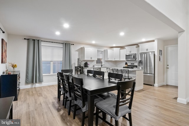 dining space with light hardwood / wood-style flooring and sink