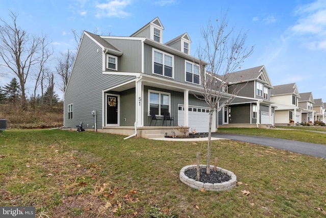 view of front facade with covered porch, a garage, a front yard, and central AC