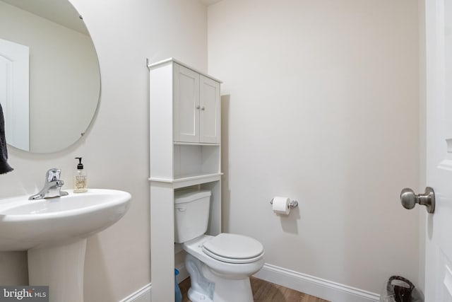 bathroom with wood-type flooring, toilet, and sink