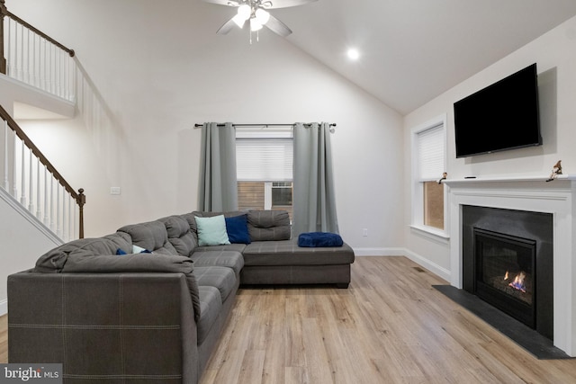 living room with ceiling fan, high vaulted ceiling, and light hardwood / wood-style flooring