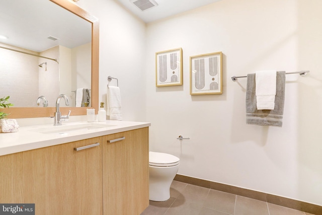 bathroom with toilet, vanity, and tile patterned floors