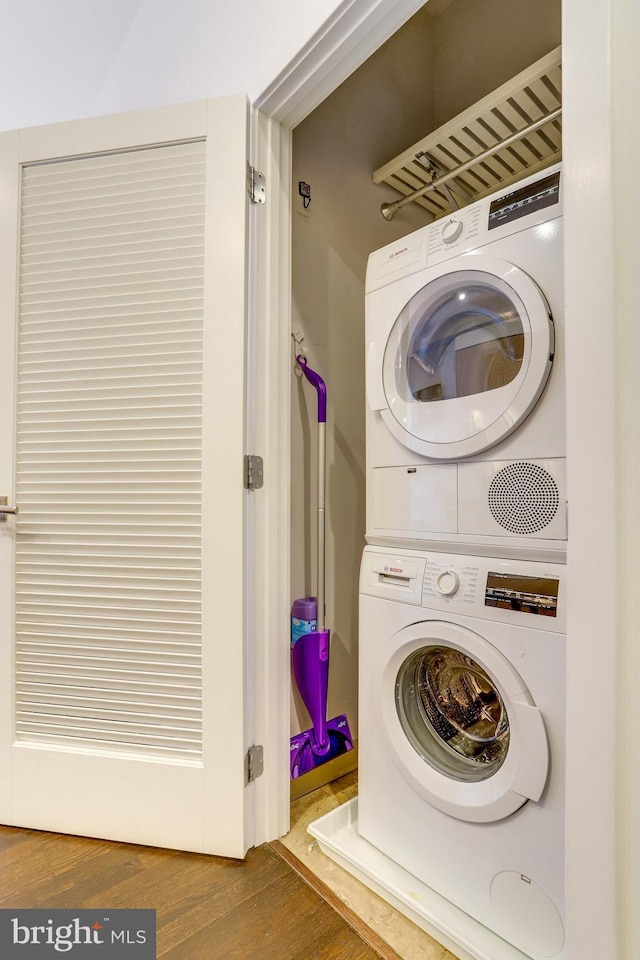 laundry area with dark hardwood / wood-style flooring and stacked washer and dryer