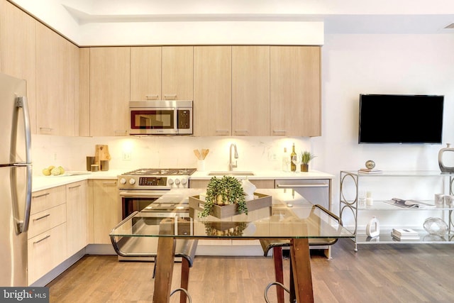 kitchen featuring light brown cabinetry, sink, appliances with stainless steel finishes, and light hardwood / wood-style flooring