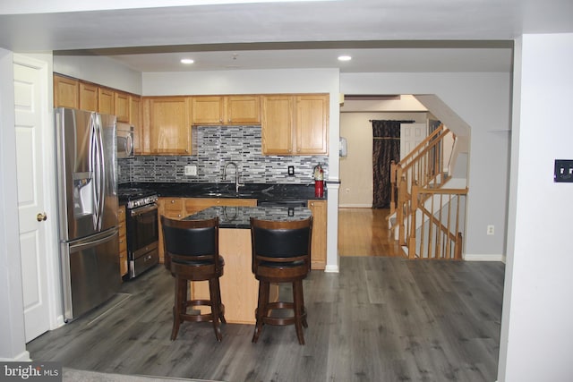 kitchen with sink, dark wood-type flooring, a kitchen breakfast bar, tasteful backsplash, and appliances with stainless steel finishes