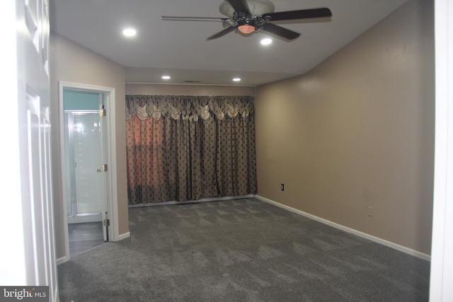 spare room featuring ceiling fan and dark carpet