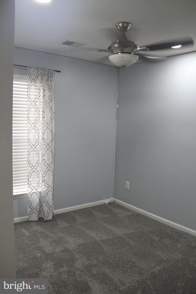 unfurnished room featuring dark colored carpet, plenty of natural light, and ceiling fan