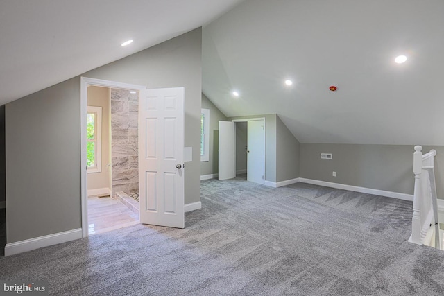 additional living space featuring light carpet and vaulted ceiling