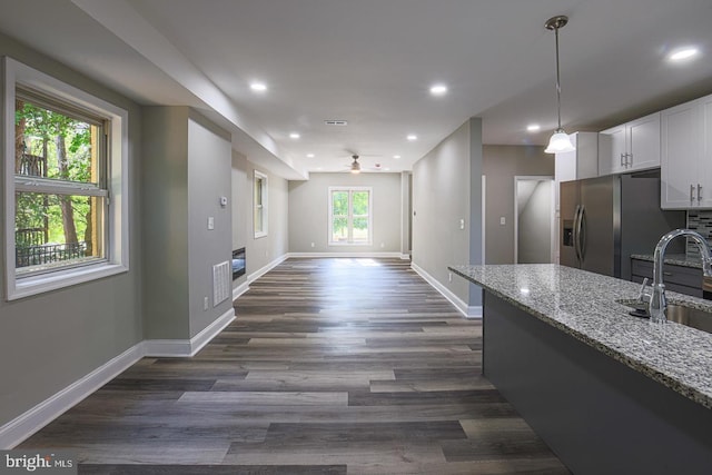 kitchen with light stone counters, sink, white cabinets, and plenty of natural light