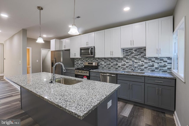 kitchen with white cabinets, stainless steel appliances, hanging light fixtures, and sink