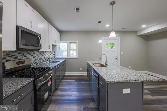 kitchen with light stone countertops, white cabinetry, sink, stainless steel appliances, and dark hardwood / wood-style floors