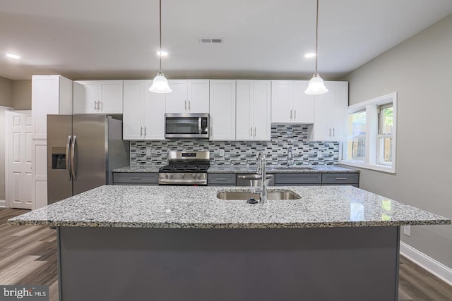 kitchen with a kitchen island with sink, pendant lighting, white cabinets, and stainless steel appliances