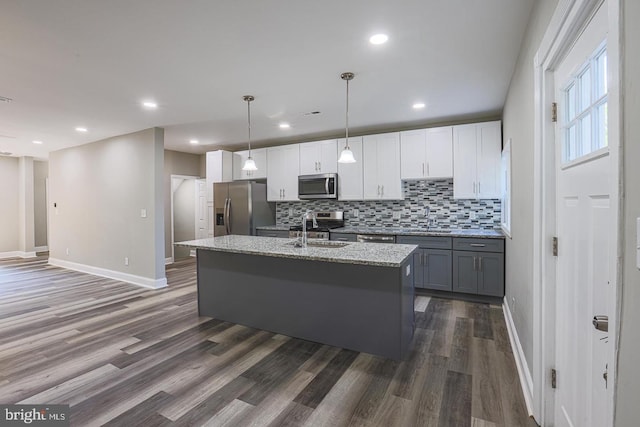 kitchen with sink, stainless steel appliances, dark hardwood / wood-style flooring, an island with sink, and decorative light fixtures