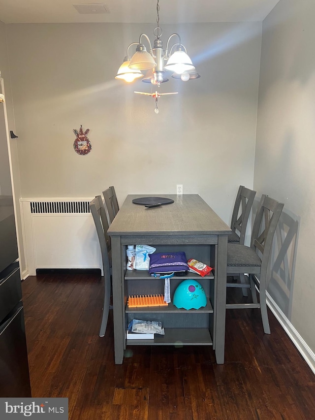 dining room featuring radiator, dark hardwood / wood-style floors, and a notable chandelier