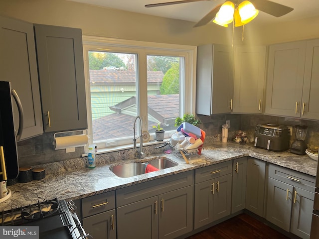 kitchen featuring backsplash, gray cabinetry, light stone counters, and sink