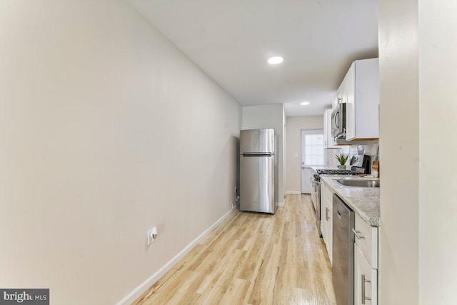 kitchen with white cabinetry, light stone countertops, tasteful backsplash, light hardwood / wood-style flooring, and appliances with stainless steel finishes