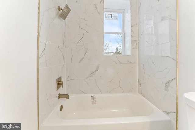 bathroom with toilet and tiled shower / bath