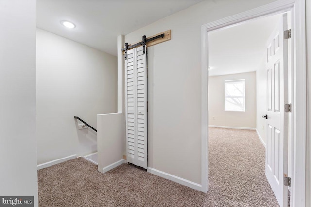 corridor with carpet flooring and a barn door