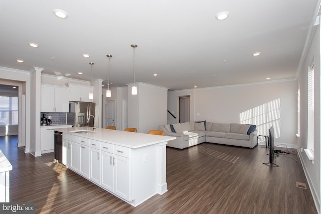 kitchen with stainless steel refrigerator with ice dispenser, white cabinetry, hanging light fixtures, an island with sink, and backsplash