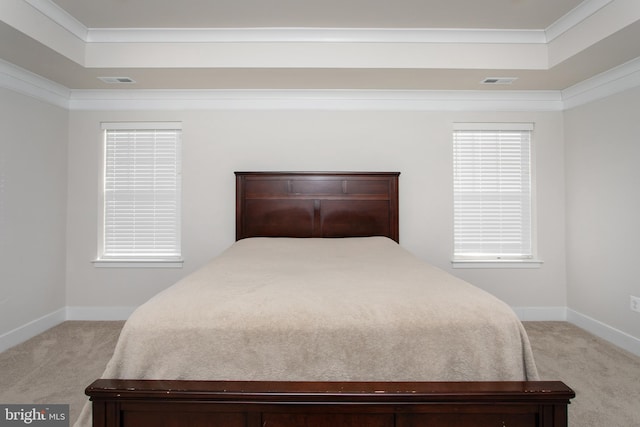 bedroom with crown molding, a tray ceiling, and light colored carpet