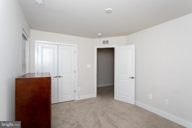 unfurnished bedroom featuring light colored carpet and a closet