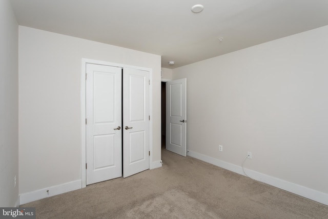 unfurnished bedroom with light carpet and a closet