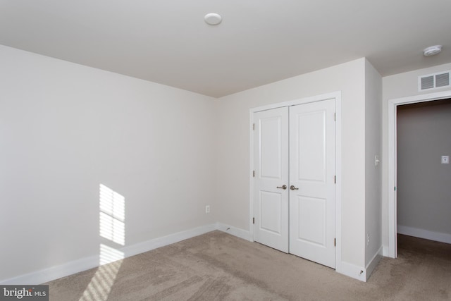 unfurnished bedroom featuring light colored carpet and a closet