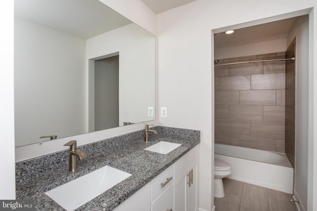 full bathroom featuring vanity, tiled shower / bath, and toilet