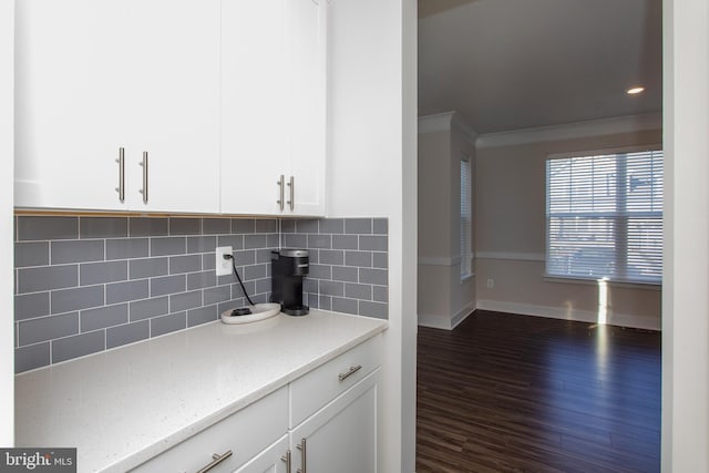 kitchen with crown molding, backsplash, light stone counters, white cabinets, and dark hardwood / wood-style flooring