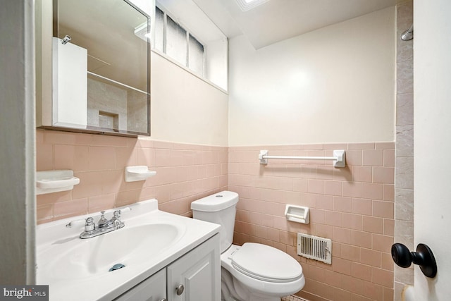 bathroom with vanity, tile walls, and toilet