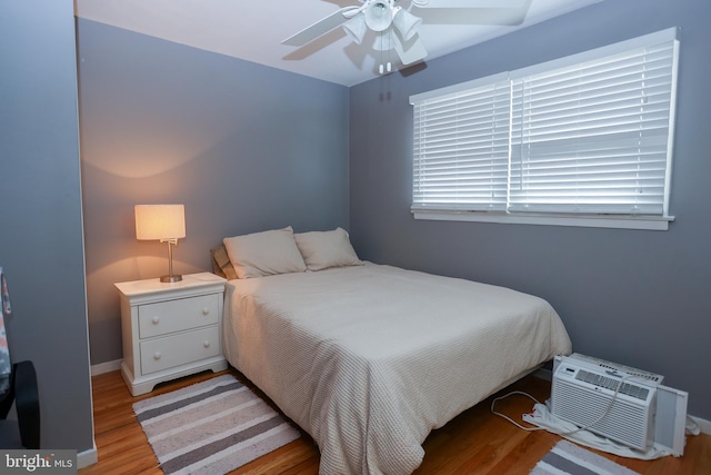 bedroom featuring ceiling fan, light hardwood / wood-style floors, and a wall mounted air conditioner