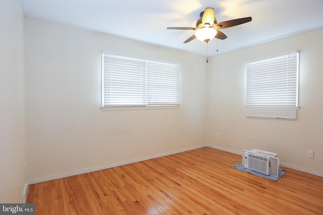 spare room featuring a wall mounted AC, ceiling fan, and light wood-type flooring