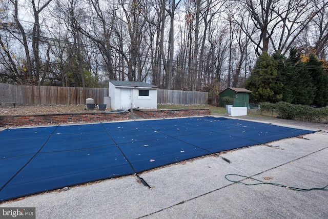 view of swimming pool featuring a patio area and a storage shed