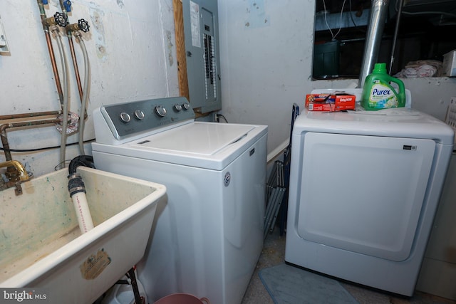 clothes washing area featuring independent washer and dryer, electric panel, and sink