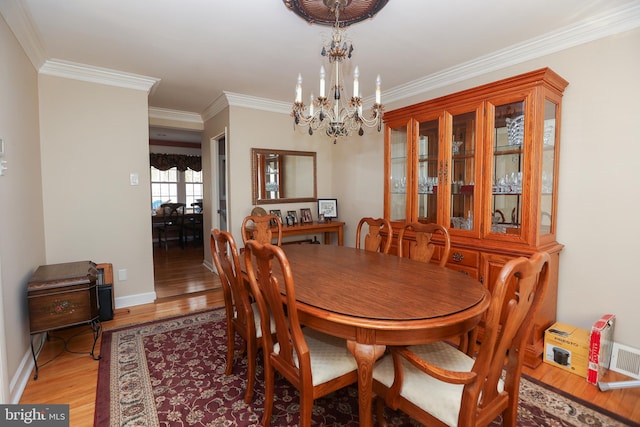 dining area with crown molding, light hardwood / wood-style flooring, and a chandelier