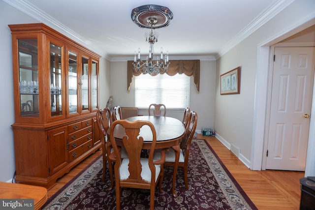 dining area featuring light hardwood / wood-style flooring, crown molding, and a notable chandelier