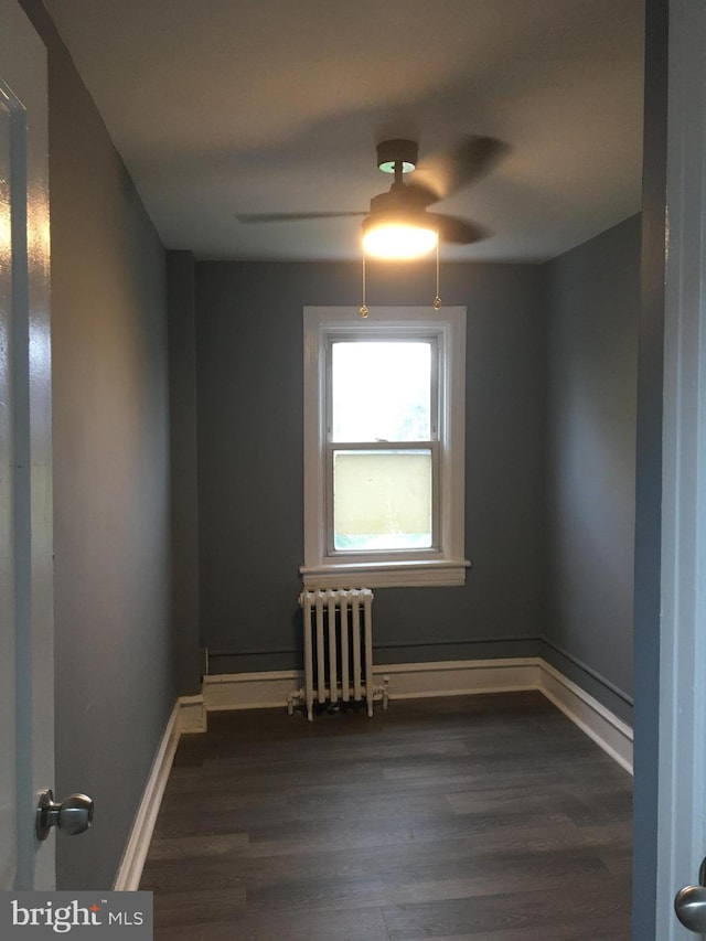 unfurnished room featuring radiator and dark wood-type flooring