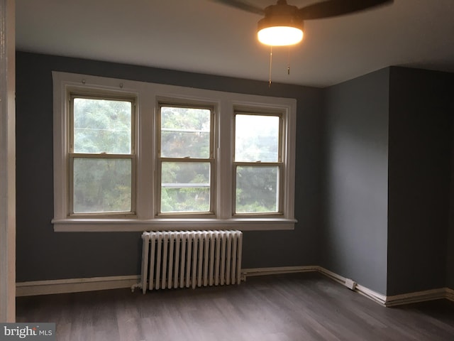 spare room featuring ceiling fan, wood-type flooring, and radiator heating unit