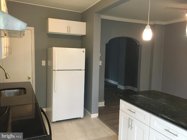 kitchen featuring sink, dark stone countertops, white cabinets, white fridge, and hanging light fixtures