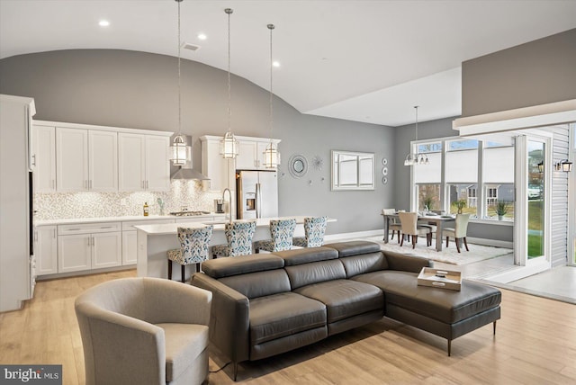 living room with sink, high vaulted ceiling, and light wood-type flooring