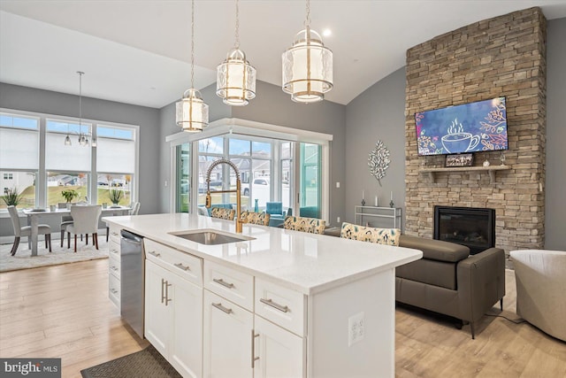 kitchen featuring white cabinetry, sink, hanging light fixtures, light hardwood / wood-style floors, and a kitchen island with sink