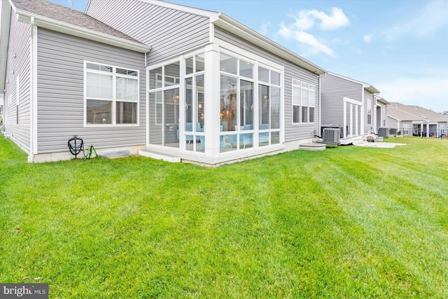 back of house with a sunroom, a yard, and central AC