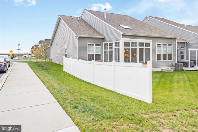 view of side of property with central air condition unit, a sunroom, and a yard