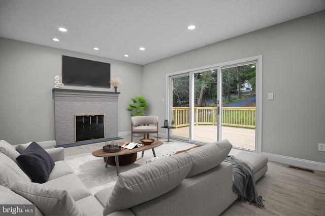 living room with a fireplace and light wood-type flooring