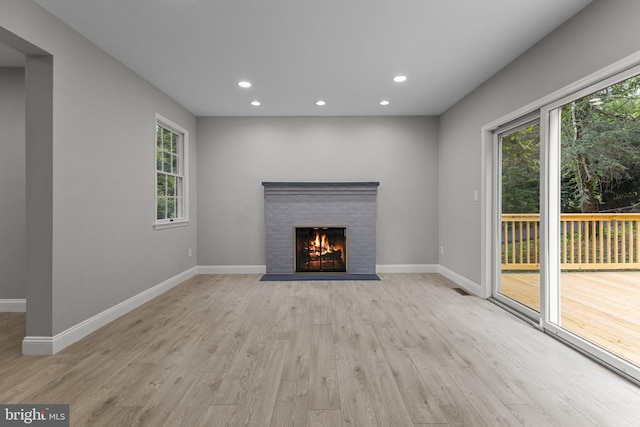 unfurnished living room with a fireplace and light hardwood / wood-style floors