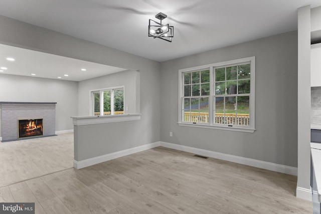 unfurnished dining area featuring a fireplace and light hardwood / wood-style floors